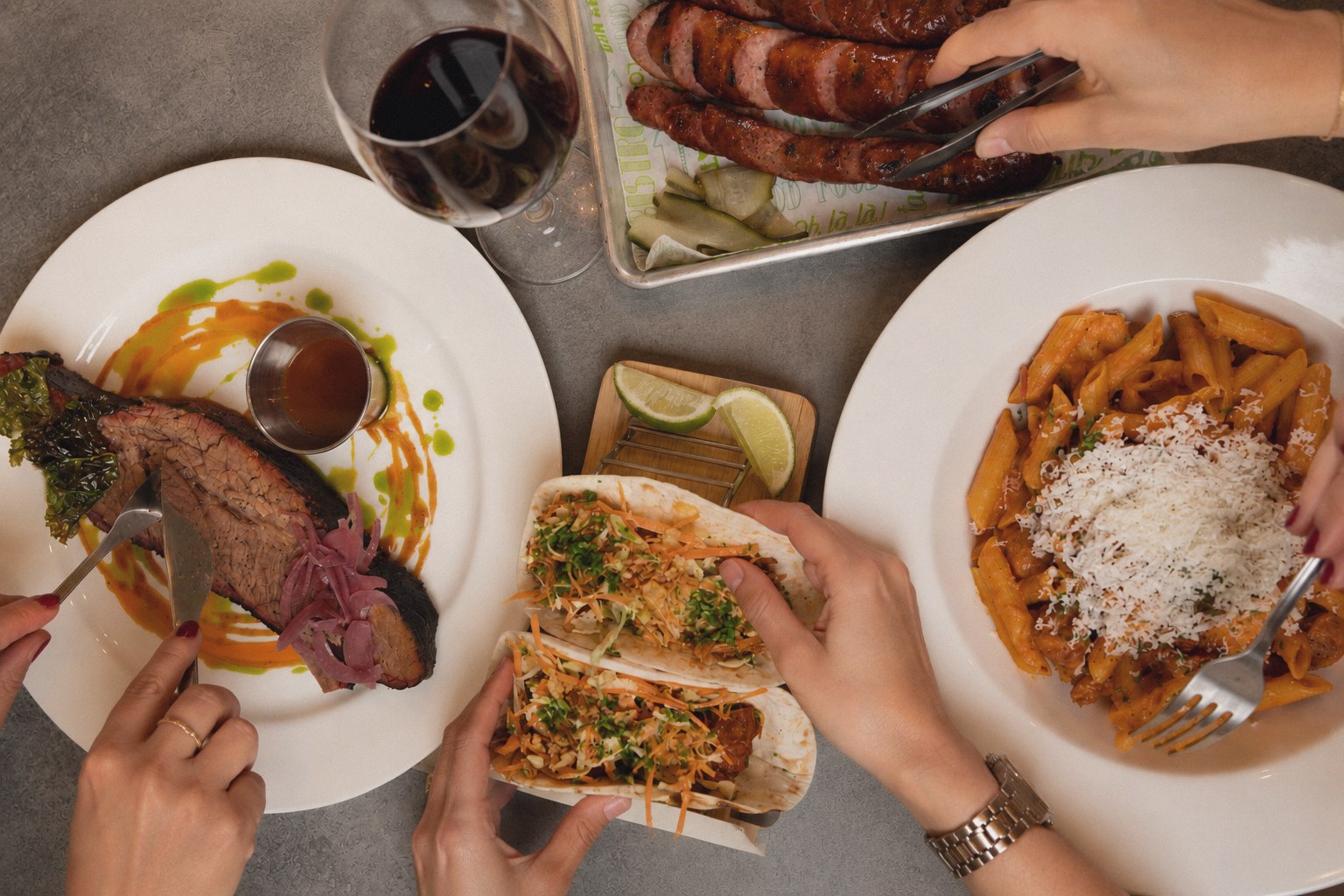 A shared table of smoked brisket, tacos, pasta and sausages at Fumiglia