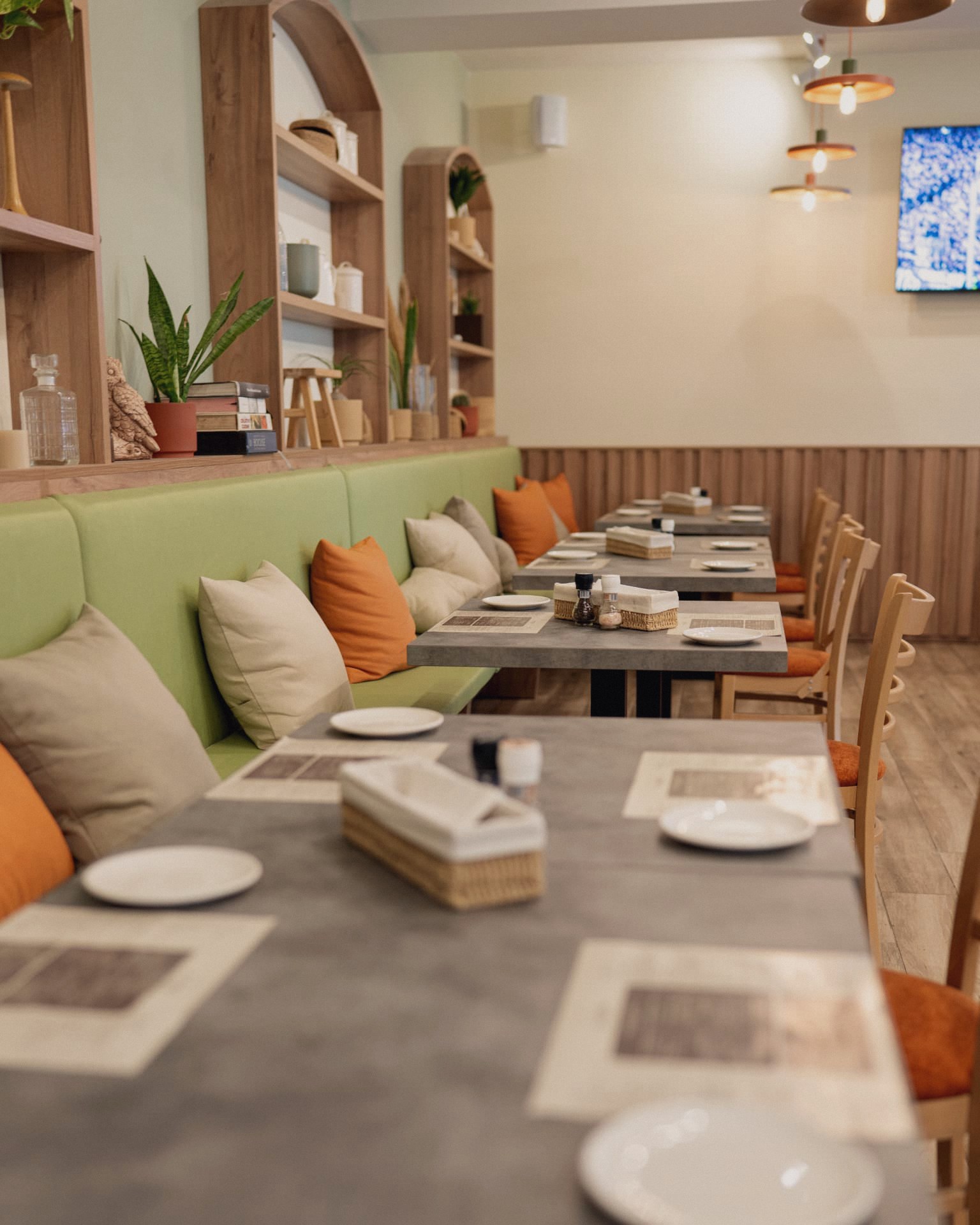 Green banquette seating with terracotta cushions and wooden shelving