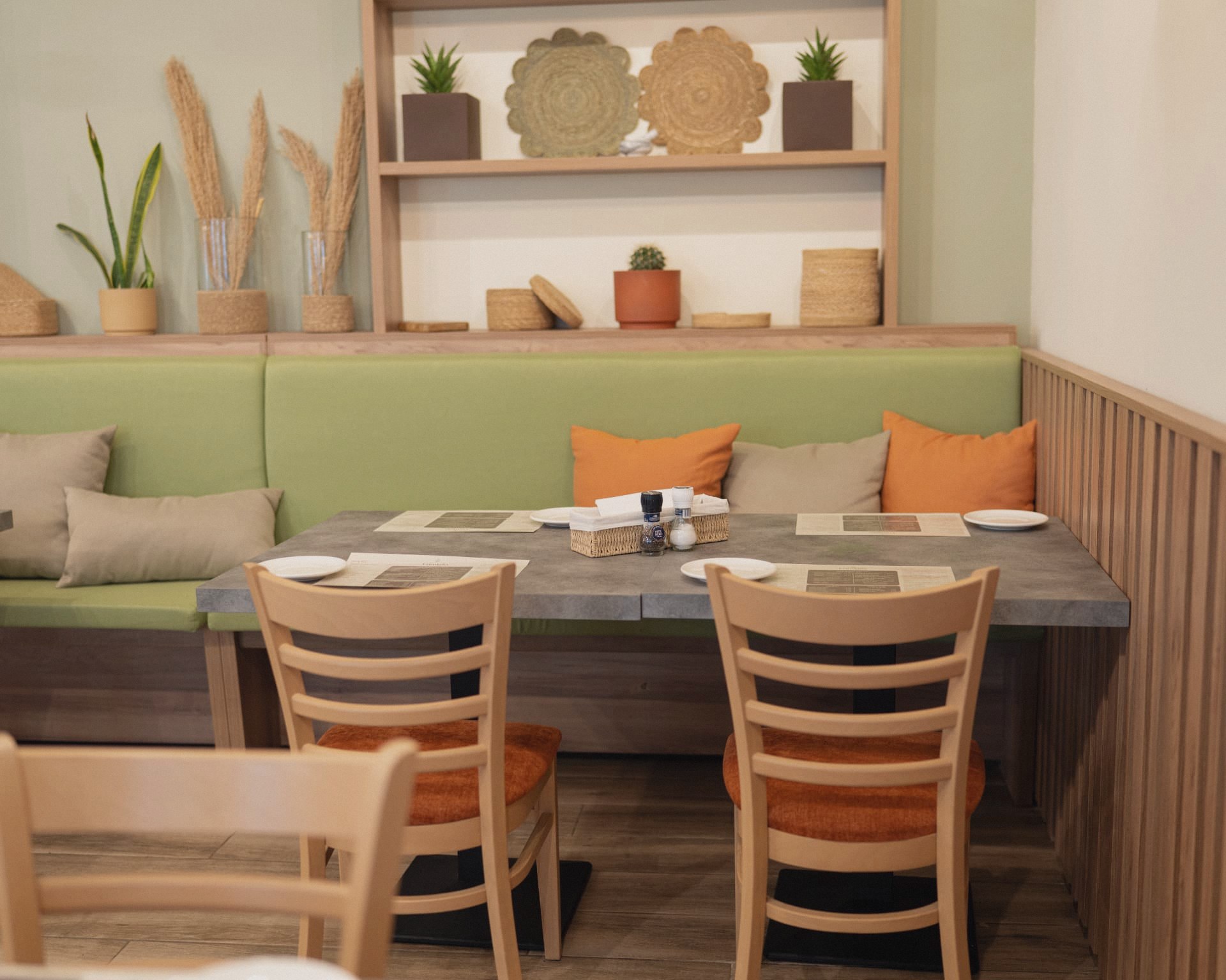 A set table beside the green banquette with dried grasses and woven decor