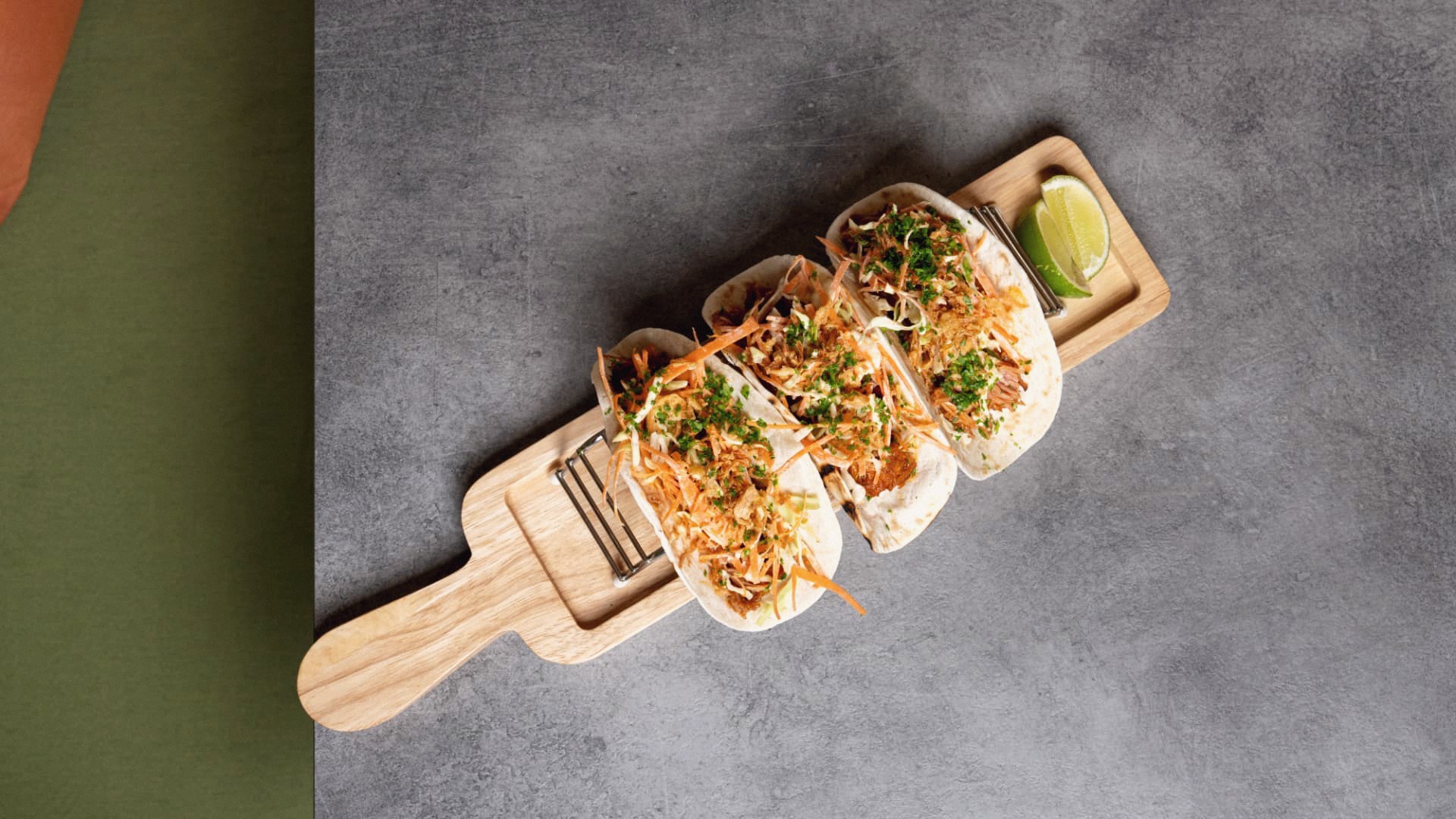 Pulled meat tacos on a wooden board with lime